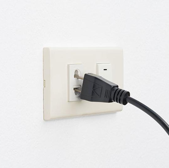 Inspecting a power cable plugged into a wall outlet
